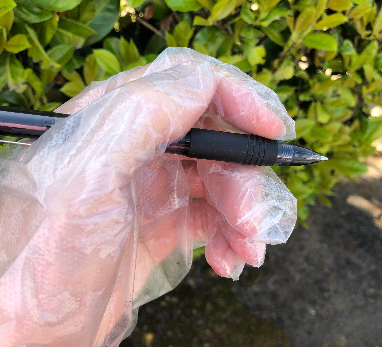 hand in a plastic glove holding a pen